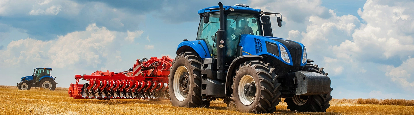 Two blue tractors harvesting tillage